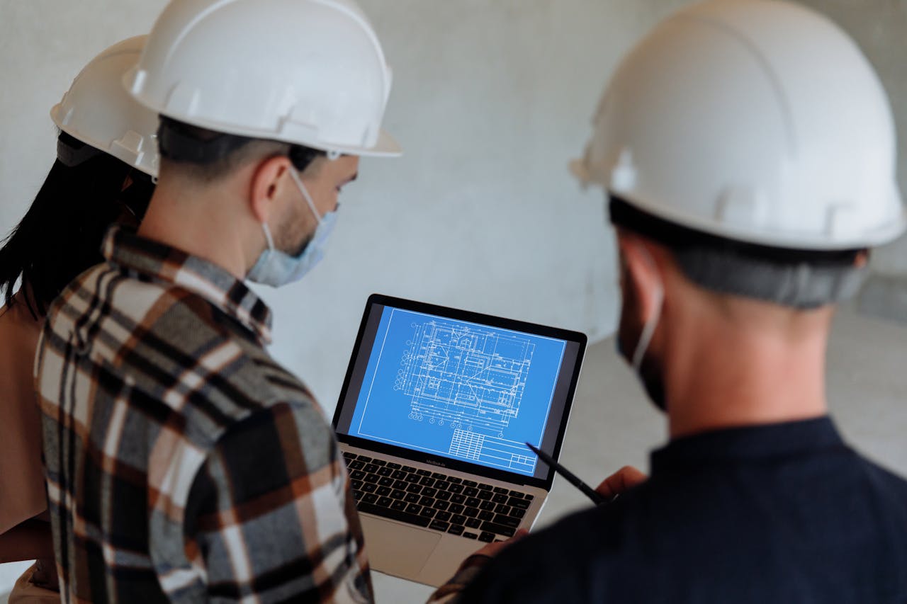 Crafting Captivating Headlines: Your awesome post title goes here Engineers wearing hard hats and masks review a construction blueprint on a laptop indoors.